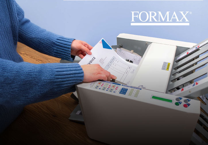 Person using a Formax machine with documents on a wooden surface