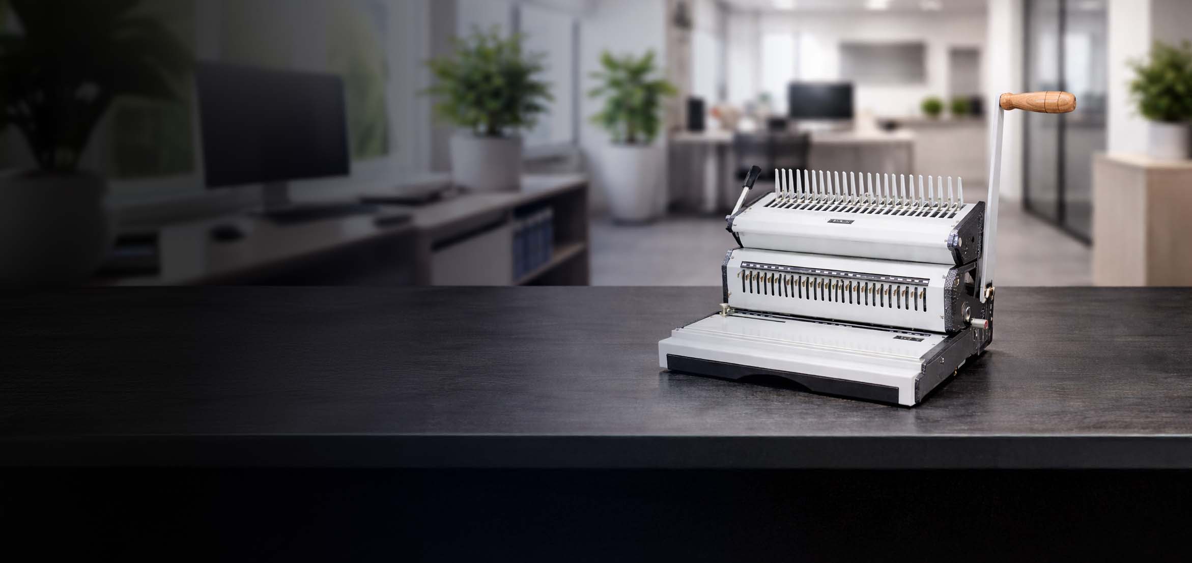Binding machine on a desk with a blurred office background