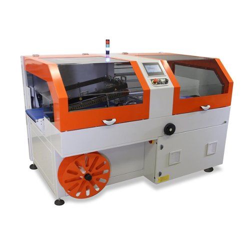 A Clamco 6750EL Auto L-Bar Sealer and Accessories featuring an orange and white design, with a compact industrial build, clear protective panels, a touchscreen control interface, and a reel for packaging material.