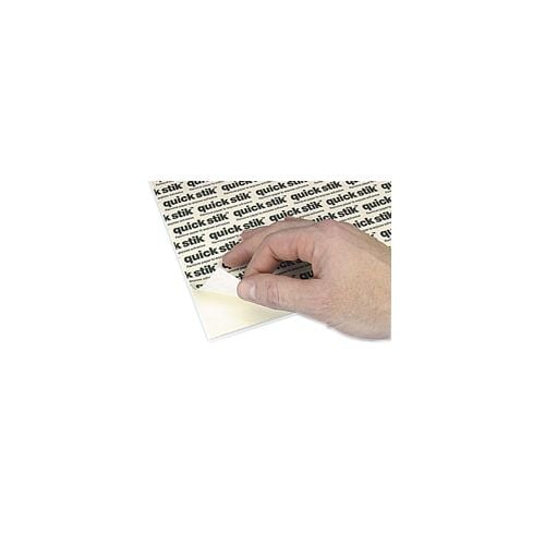 A hand peeling back the protective layer of a "White 3/16" Foam Core Permanent Adhesive 8.5" x 11" Mounting Board" with visible black "quick stik" text on the adhesive surface.